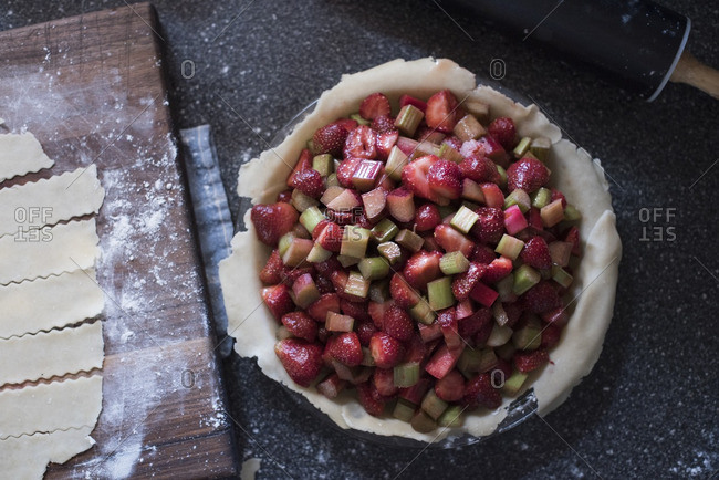 Strawberry rhubarb pie and pie dough on a wood cutting board