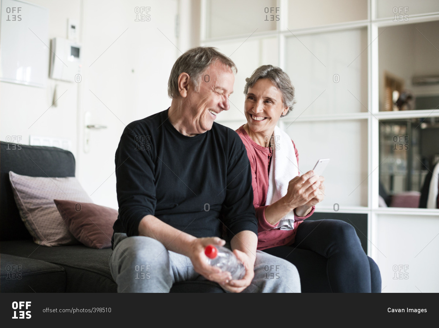 Happy senior couple using smart phone in living room