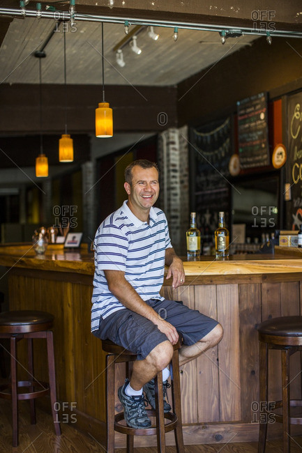 Snohomish, WA - July 30, 2015: A portrait of a happy distillery owner at his bar in Snohomish, WA