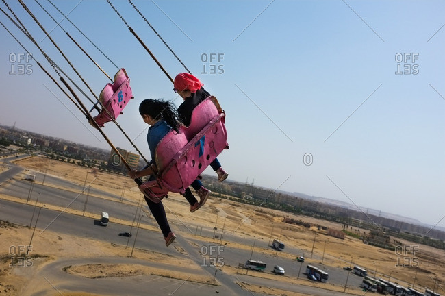 Two girls ride the swings at the Dream Park amusement park in Cairo, Egypt