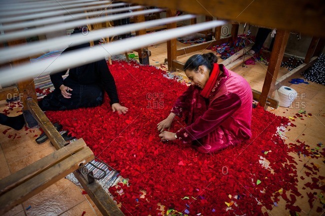 Cairo, Egypt - January 15, 2012: Women hand-tie a rug made from recycled textiles in the garbage collector district of Manshiyat Nasr in Cairo, Egypt