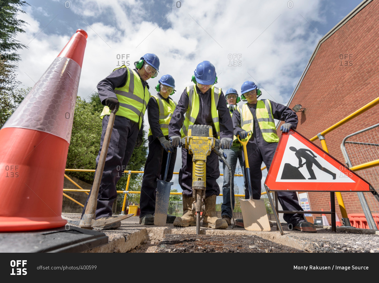 Apprentice builders training with pneumatic drill in training facility