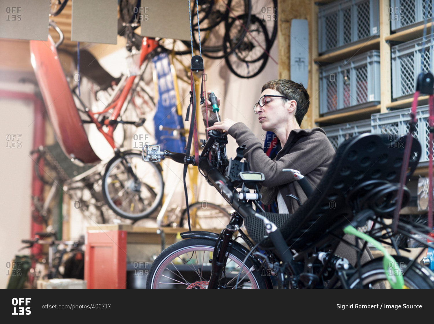 Woman in bicycle workshop repairing recumbent bicycle