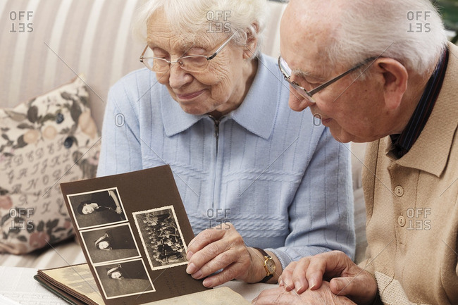 Senior couple watching old photograph album at home