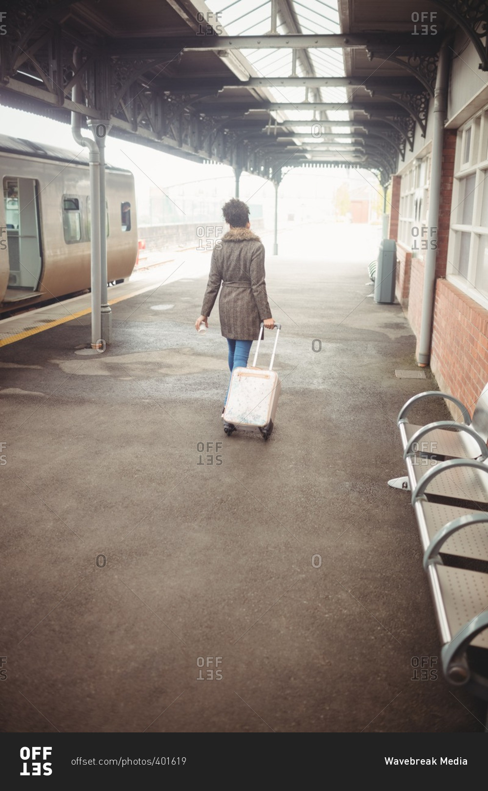 Rear view of woman carrying luggage at railroad station platform