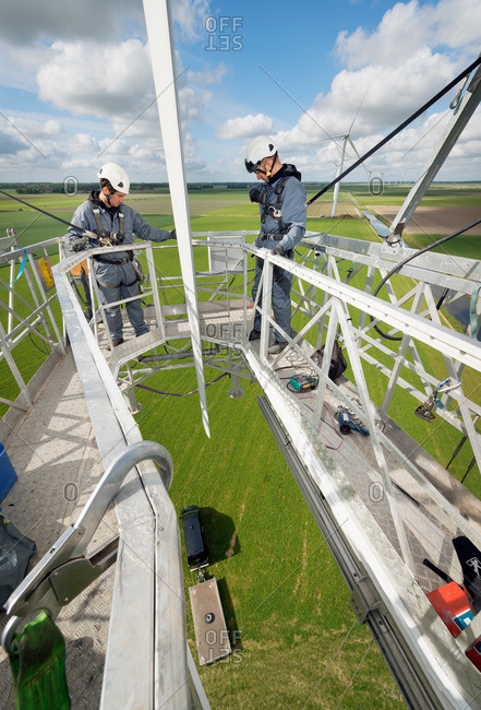 Maintenance men working on the blades of a wind turbine
