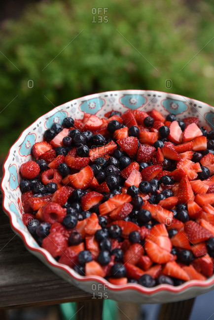 Bowl of mixed berries sitting on a wood hand rail