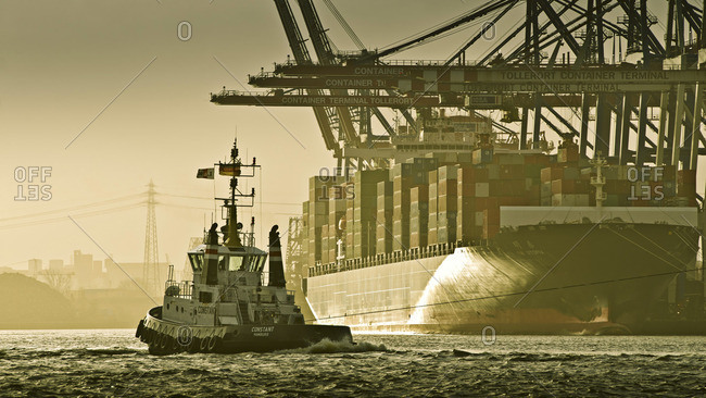 Hamburg, Germany - January 1, 2012: View of a containers ship and a tug boat in Tollerort