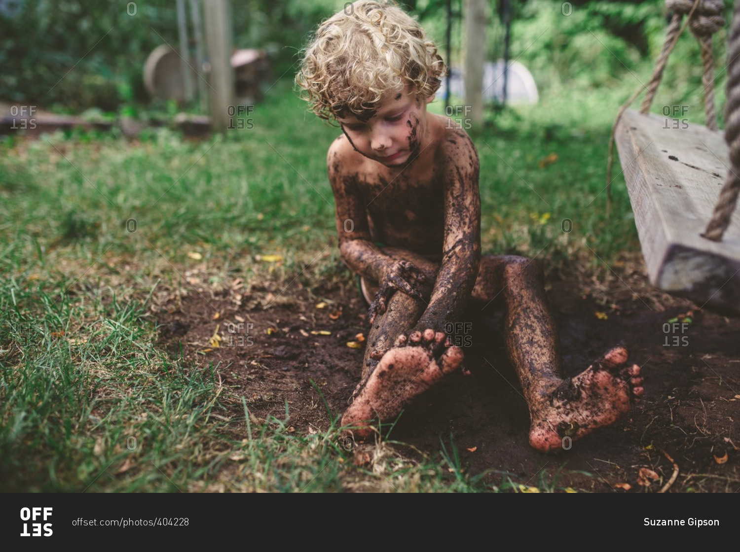 Little girl sitting in the mud on the beach stock photo 