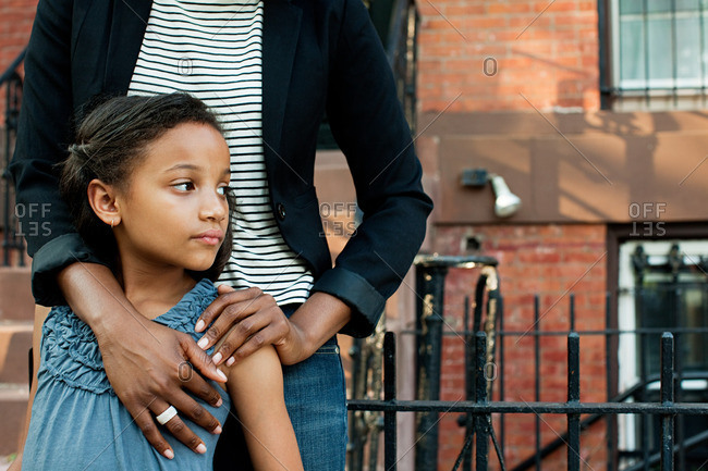 African American girl standing with mother, looking away