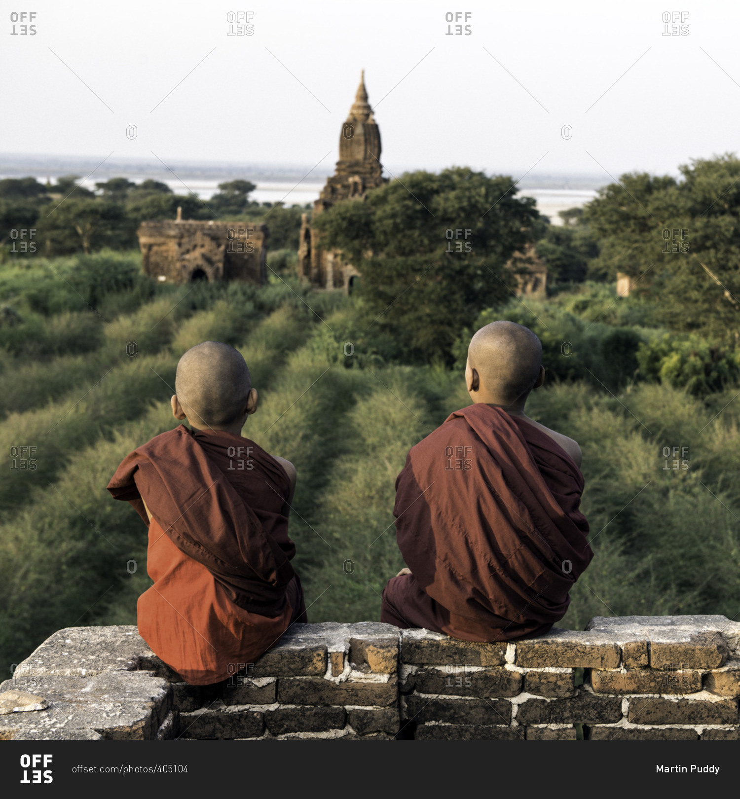 Young novice Buddhist monks sitting on a temple top looking out over ancient temple ruins