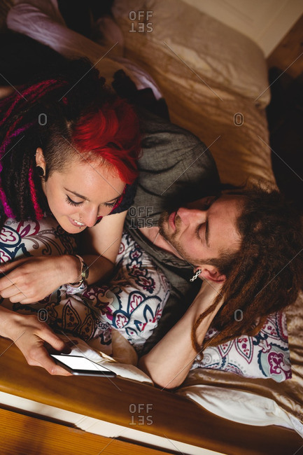 High angle view of young couple using mobile phone on bed at home