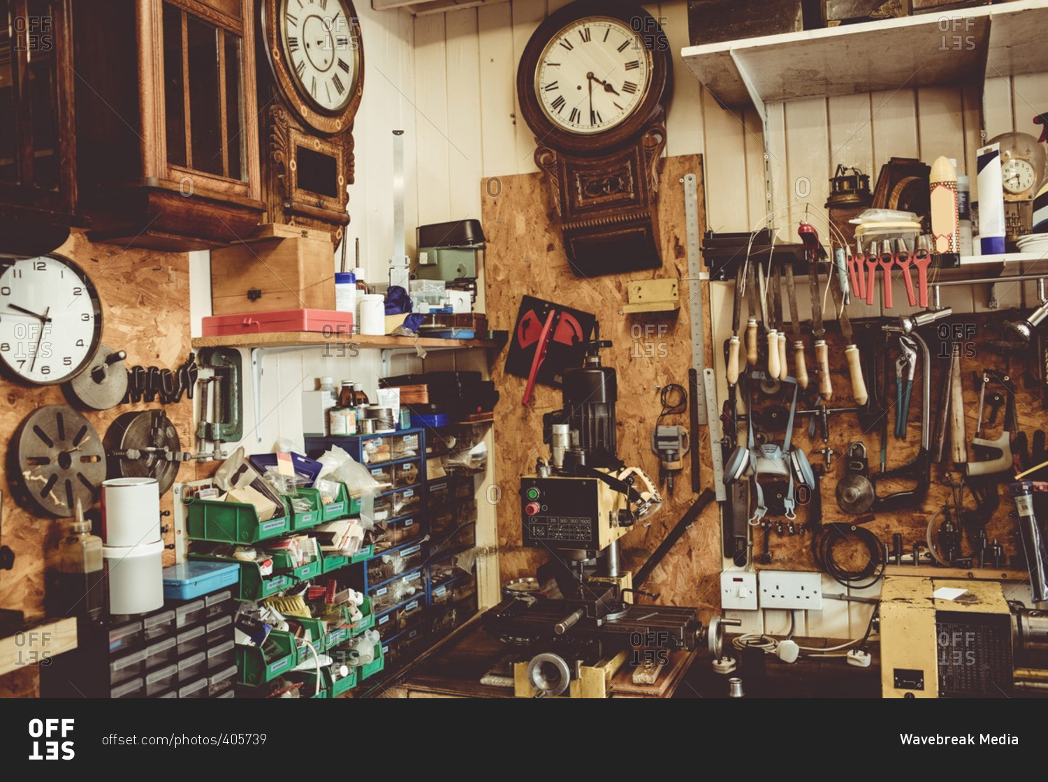 Old horologists workshop with clock repairing tools, equipment and clocks on the wall
