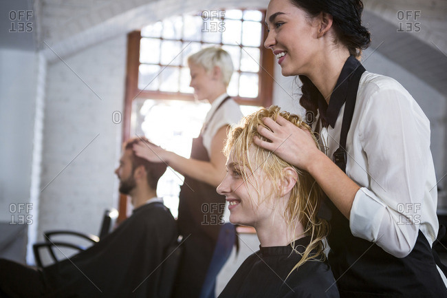 Smiling Hair Stylist Massaging Clients Hair In Salon Stock Photo