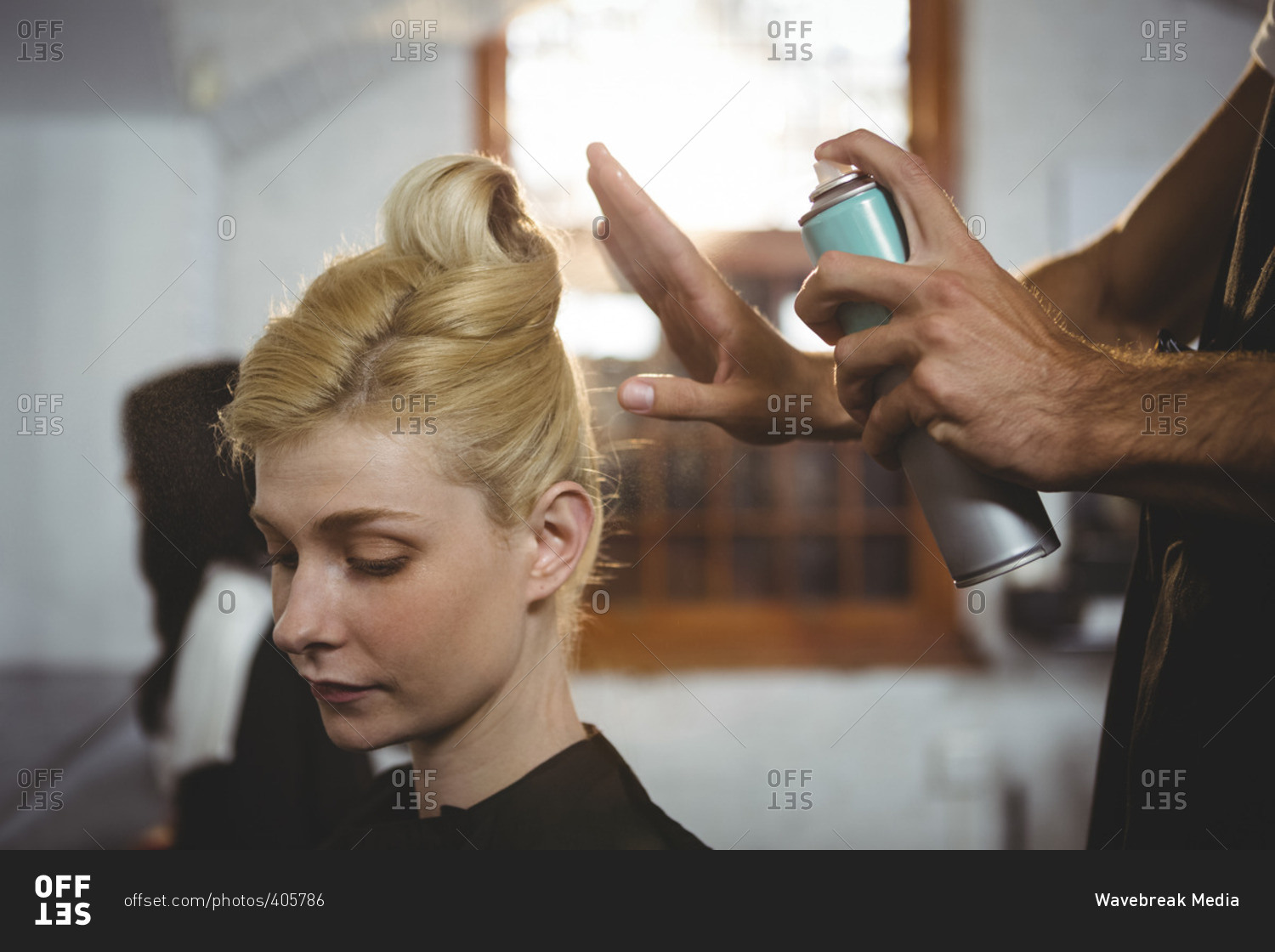 Hairdresser Styling Customers Hair With Spray In Salon Stock Photo