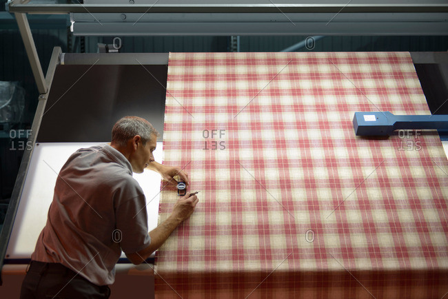 High angle view of textile worker inspecting checked woven thread in mill