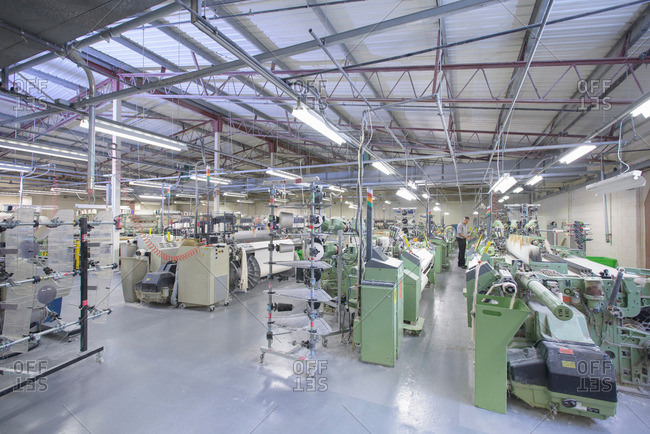 Elevated view of industrial looms and weaving machinery in textile mill