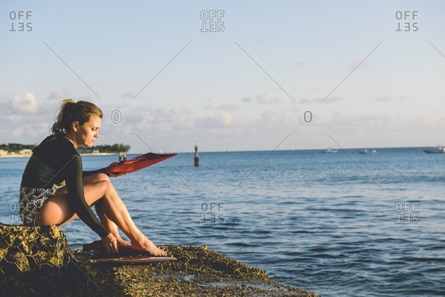 Woman putting on flippers by sea