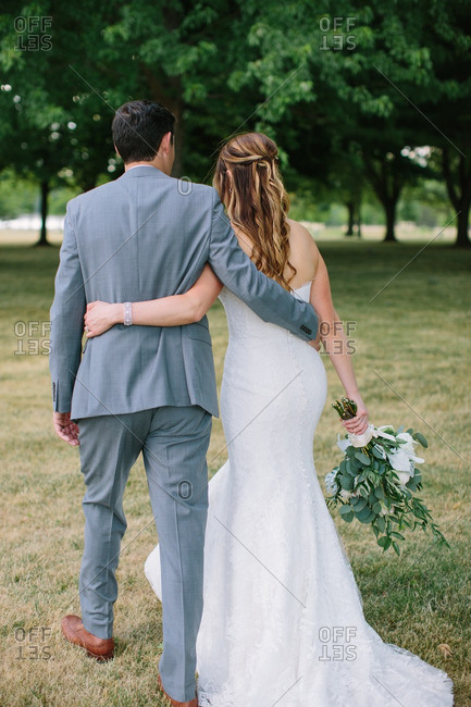 Bride and groom walking outside with arms around each other