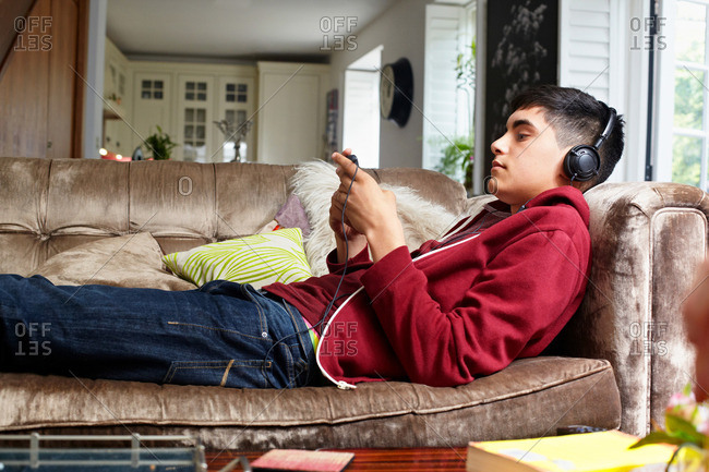 Teenage boy on sofa, listening to music