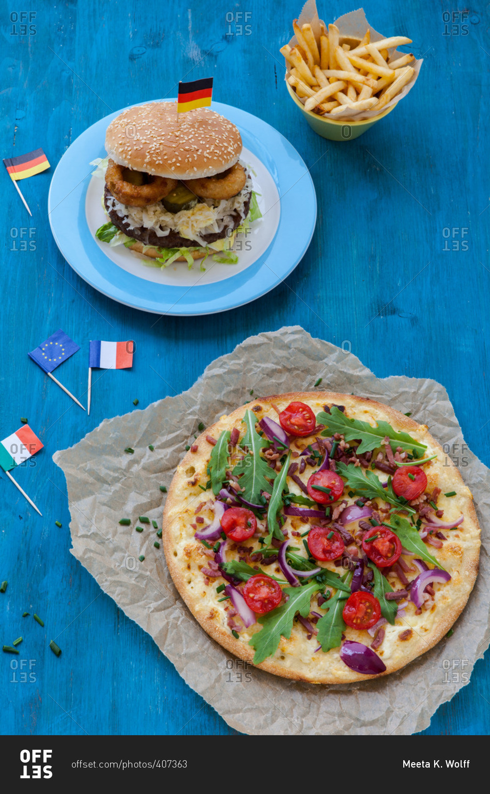 Hamburger and pizza with small Italian and German flags on a table