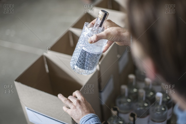 Man putting bottle of liquor into cardboard box