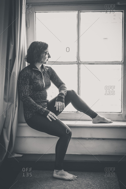 Woman sitting on windowsill looking outside