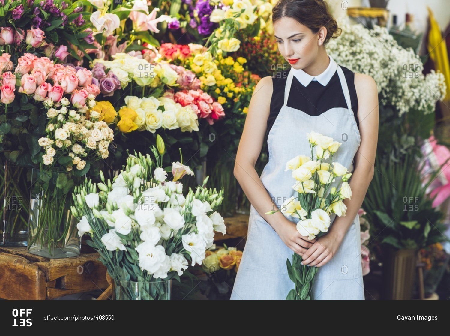 Female florist holding yellow roses in flower shop