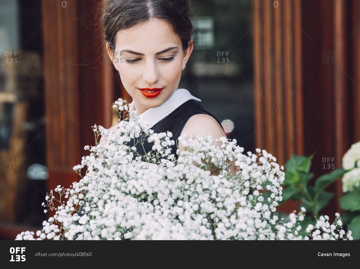 Female florist holding white flowers outside flower shop