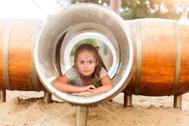 Girl lying in playground structure made of barrels