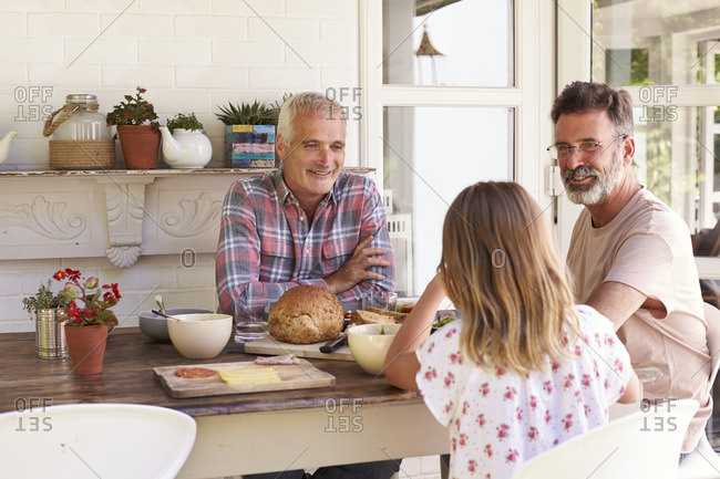 Girl eating lunch on patio with her gay male parents
