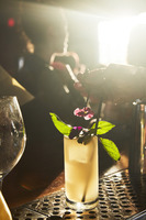 A bartender garnishing a cocktail with flowers