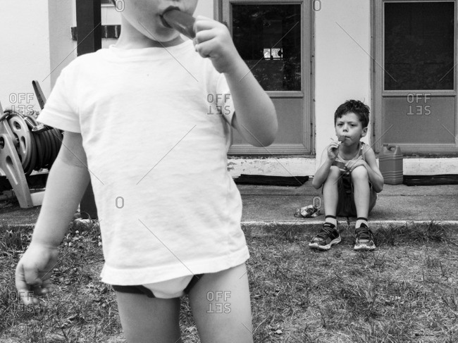 Boys eating popsicles on a porch outside