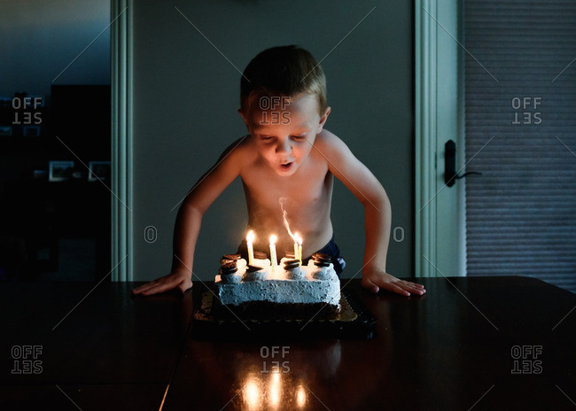 Young boy blowing out birthday candles on cake