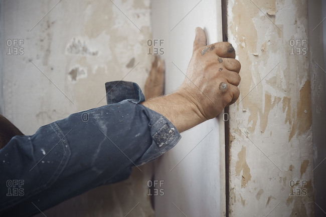 Hands of construction man hanging drywall