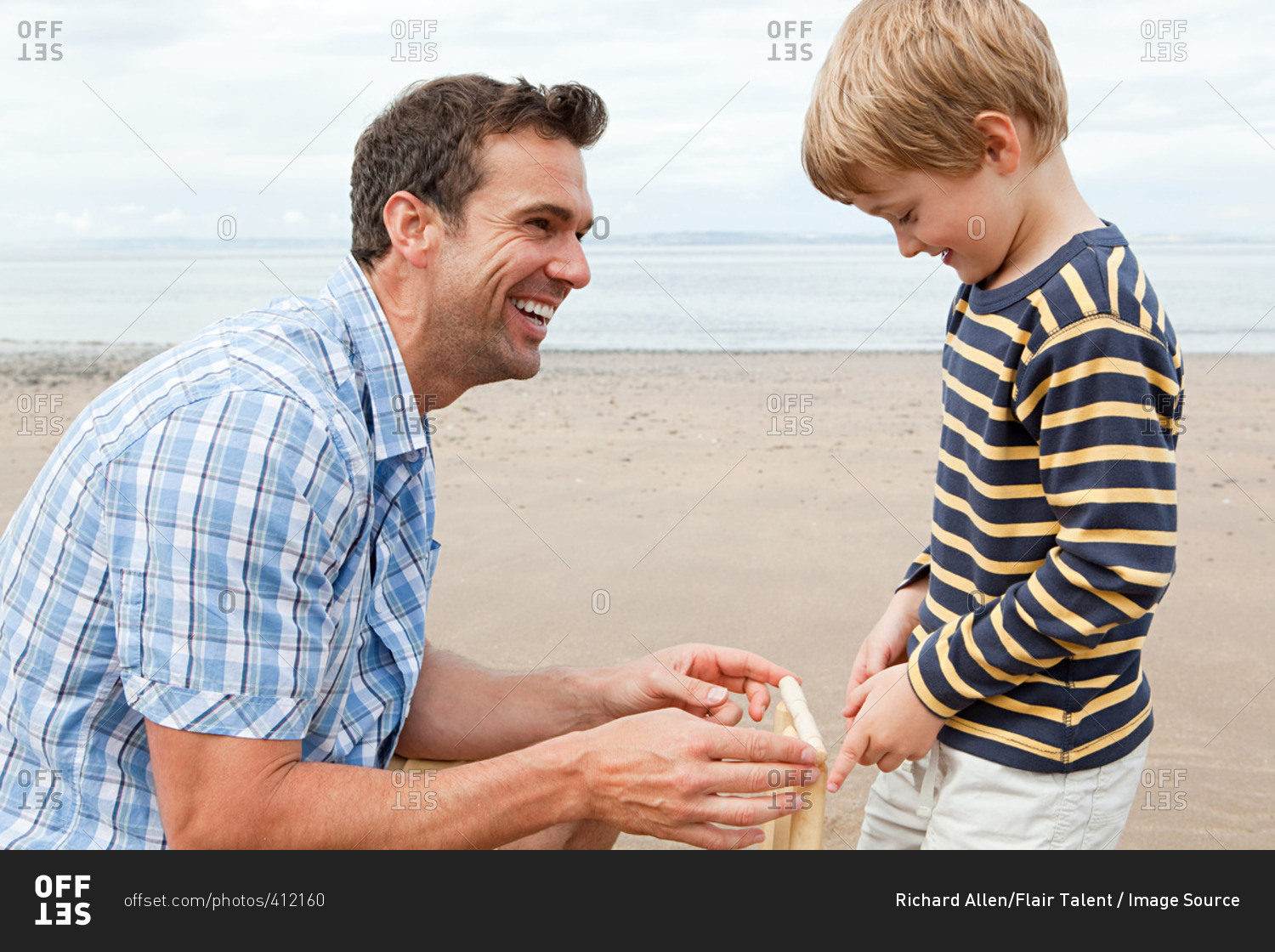 Father and son on beach with cricket stumps