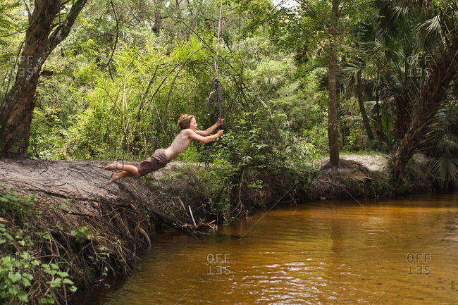 Boy leaping on forest rope swing