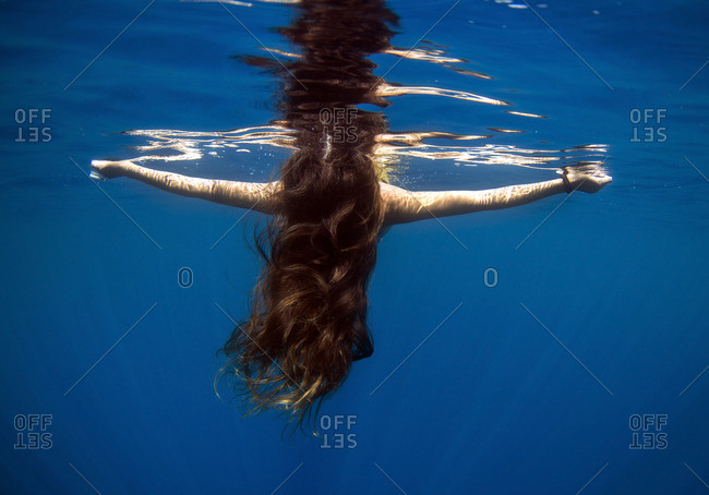 Underwater view of woman floating at the water's surface