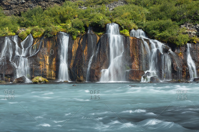 Icelandic waterfalls falling into fast-flowing glacial river