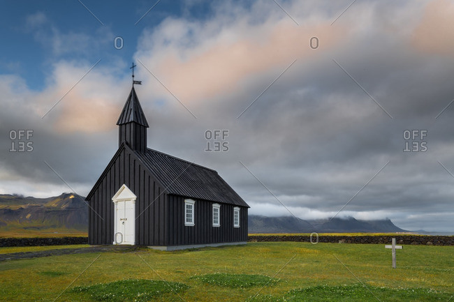 Black wooden church in remote Icelandic location with evening sky