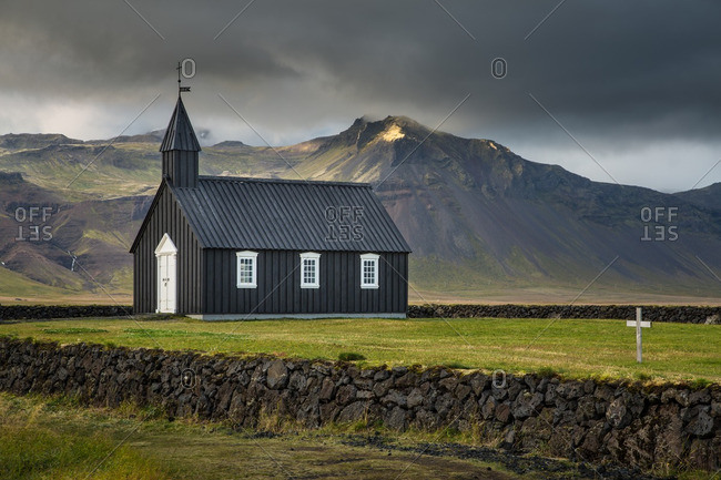 Black wooden church in remote Icelandic location with stormy sky