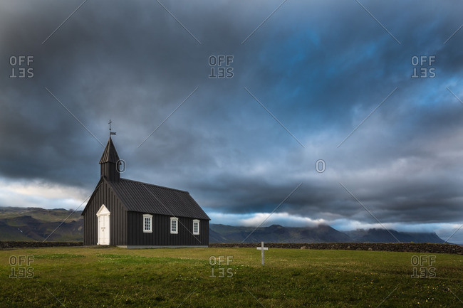 Black wooden church in remote Icelandic location with storm clouds