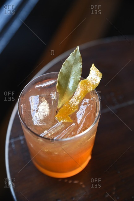 Overhead view of a cocktail with bay leaf and orange rind