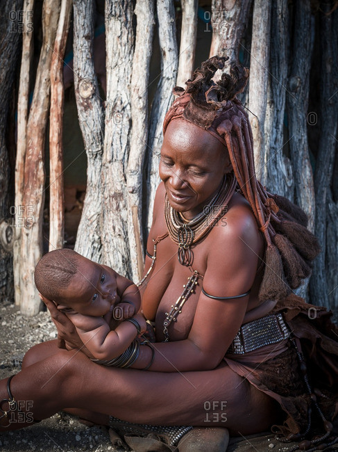 Namibia, Africa - May 30, 2014: Himba mother with her child in front of a traditional hut in Namibia