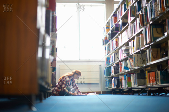 Young female college student working on library floor