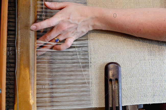Hands of young woman using loom