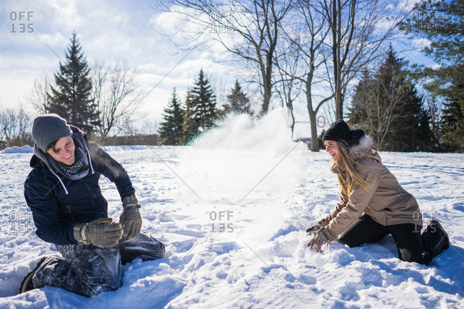 Young couple fooling around in snow, throwing snow