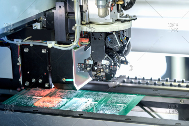 Robot placing components onto circuit board in circuit board assembly factory