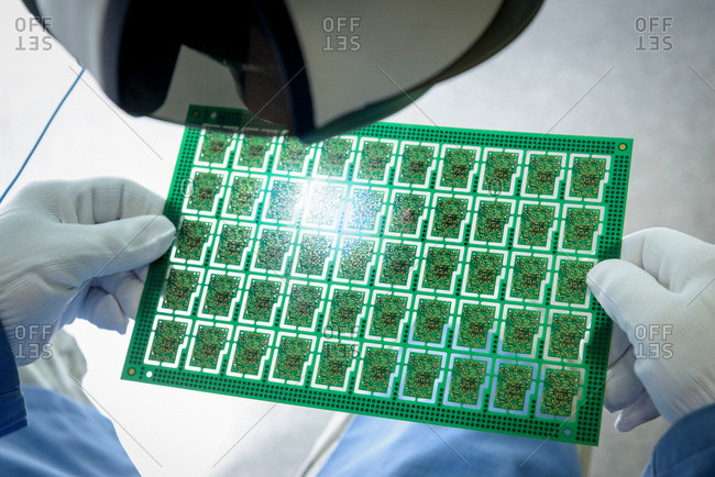Worker inspecting circuit boards in circuit board assembly factory, close up