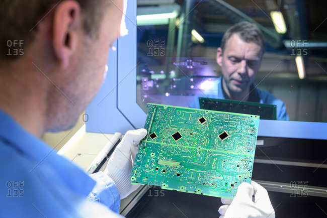 Worker inspecting circuit boards in circuit board assembly factory